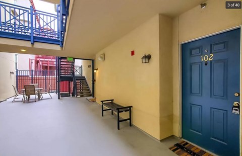 a room with a blue door and a balcony with chairs and tables
