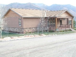 a house on the side of the road with mountains in the background