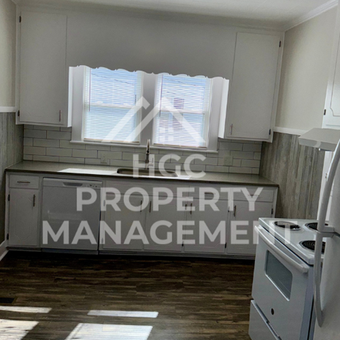 a small kitchen with white cabinets and a window