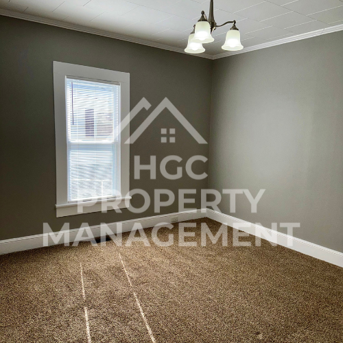 a bedroom with a window and a carpeted floor