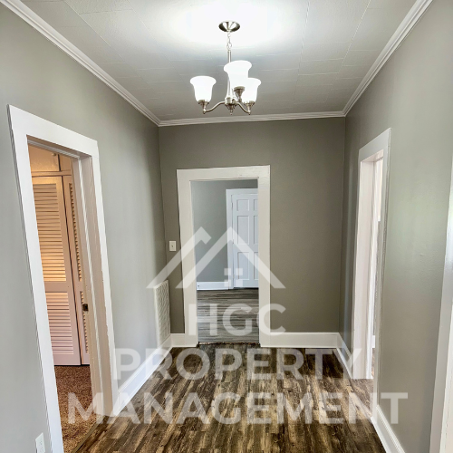 a small hallway with a mirror and a chandelier