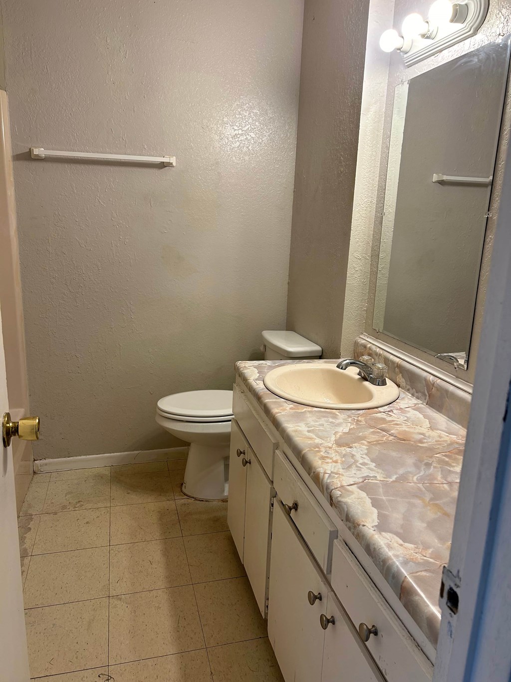 A bathroom with a toilet, sink, and mirror.
