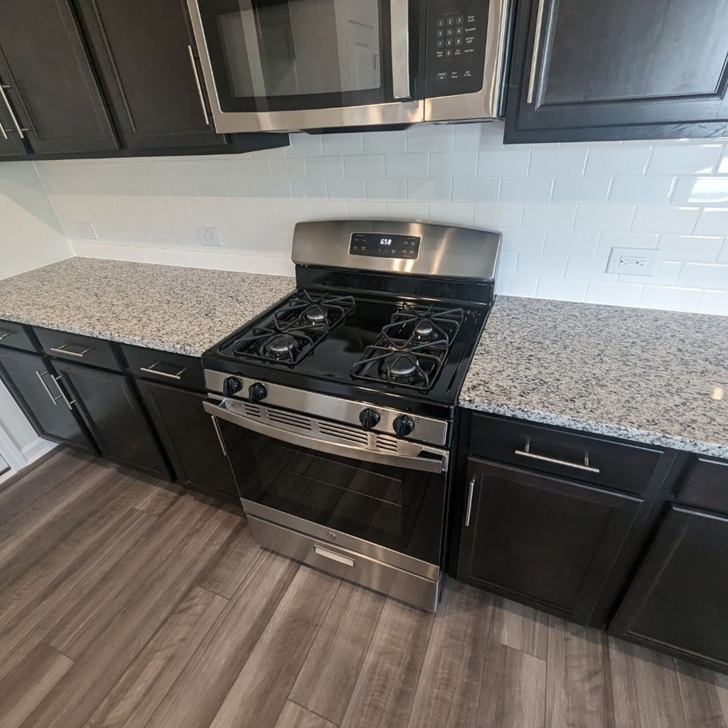 A modern kitchen with a stainless steel stove and black cabinets.
