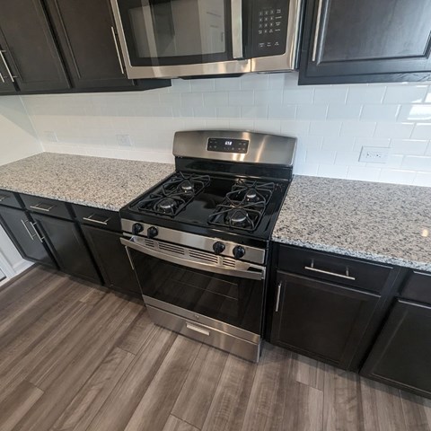 A modern kitchen with a stainless steel stove and black cabinets.