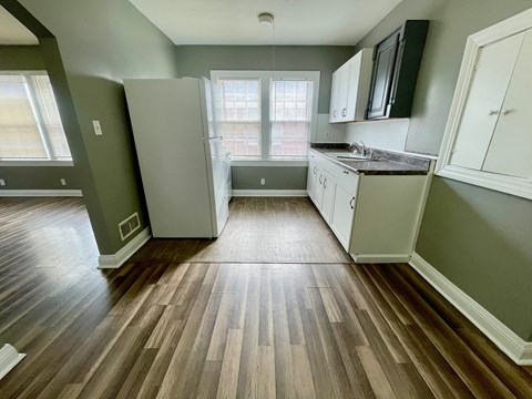 A kitchen with a refrigerator, cabinets, and a window.