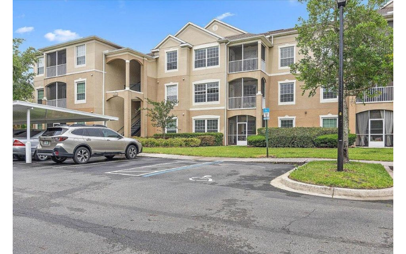 an apartment building with a car parked in a parking lot