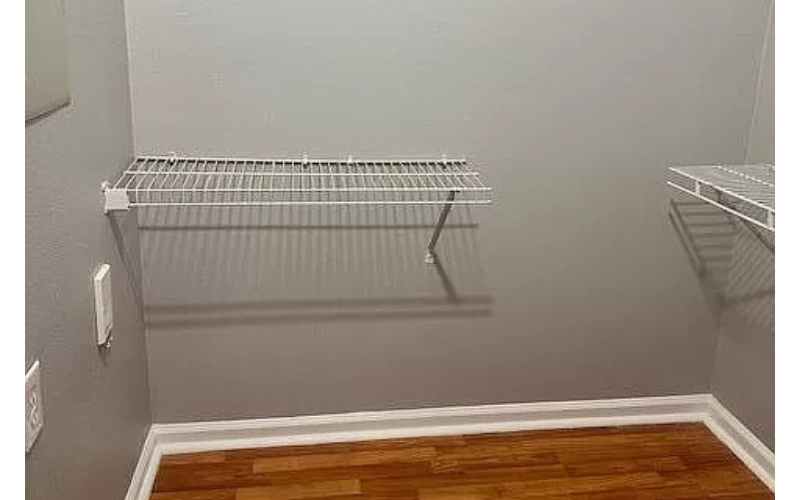 a empty closet with two shelves and a wood floor