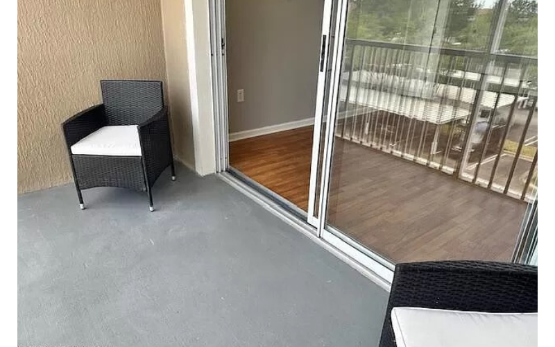 a balcony with two chairs and a sliding glass door