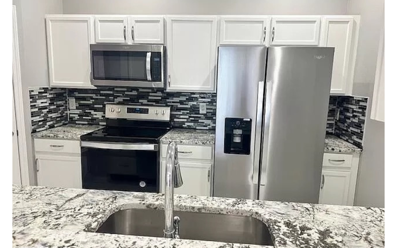 a kitchen with granite counter tops and a stainless steel refrigerator