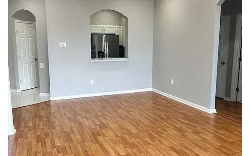 an empty living room with a wooden floor and a mirror