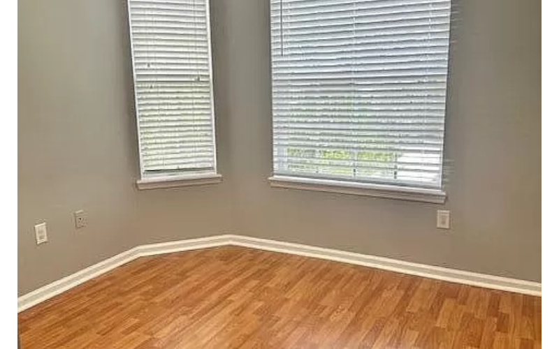 a room with a wooden floor and two windows