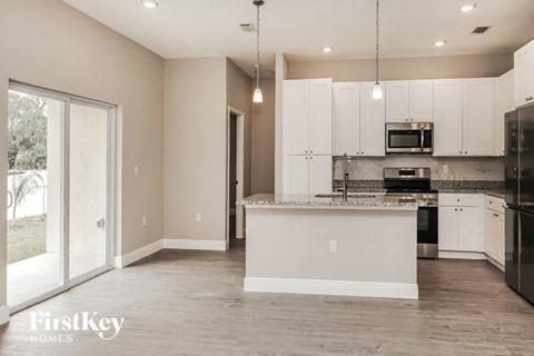 a large kitchen with white cabinets and a sliding glass door