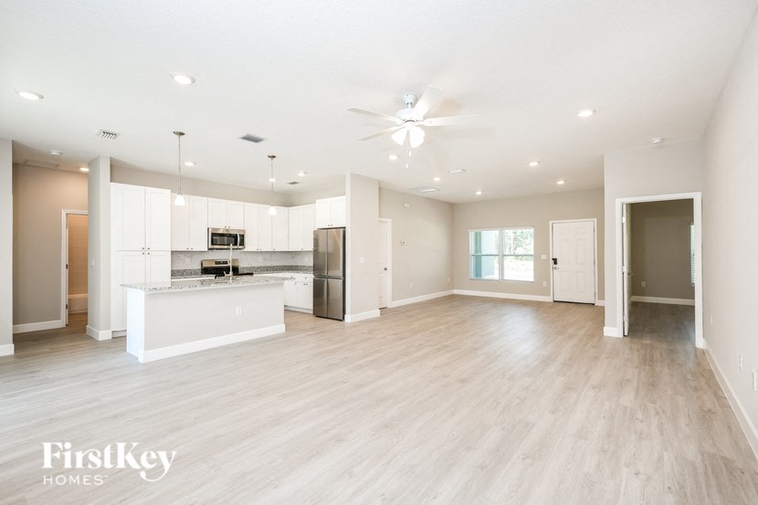 a large living room with a kitchen and a ceiling fan