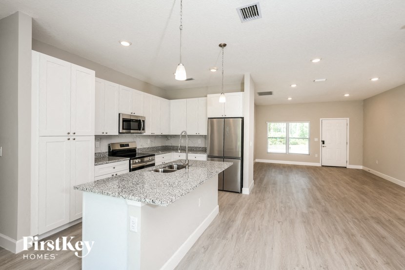 a kitchen with white cabinets and a marble counter top