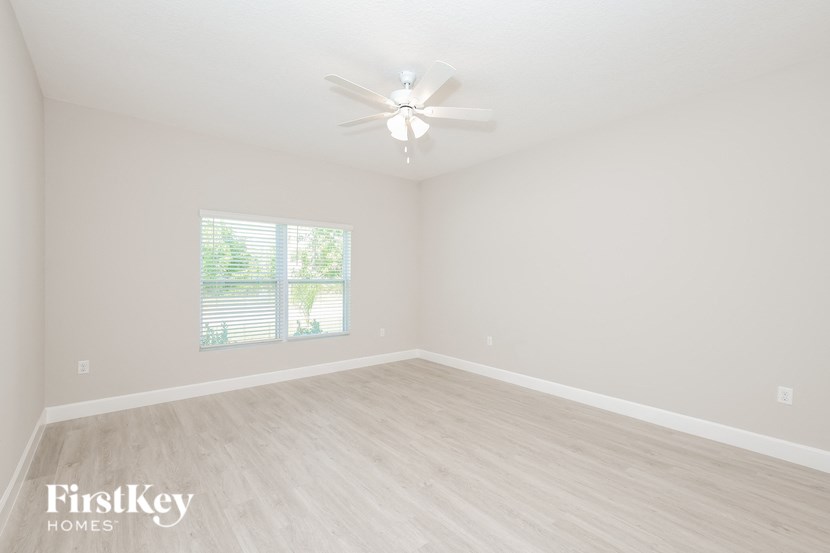 a spacious living room with white walls and a ceiling fan