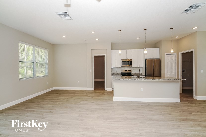 an empty living room with a kitchen with a counter top