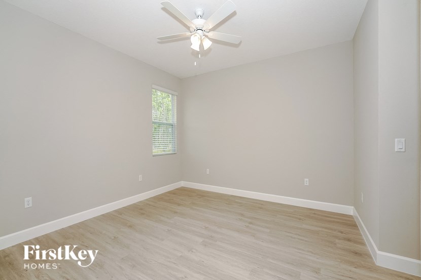 the spacious living room with hardwood floors and a ceiling fan