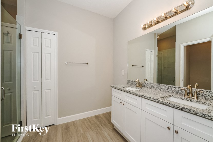 a bathroom with white cabinets and granite counter tops and a large mirror