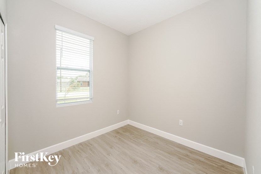 a bedroom with wood floors and white walls and a window