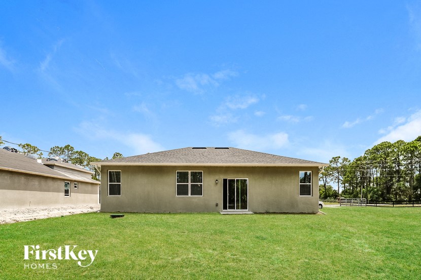 a beige house with a green lawn and a blue sky