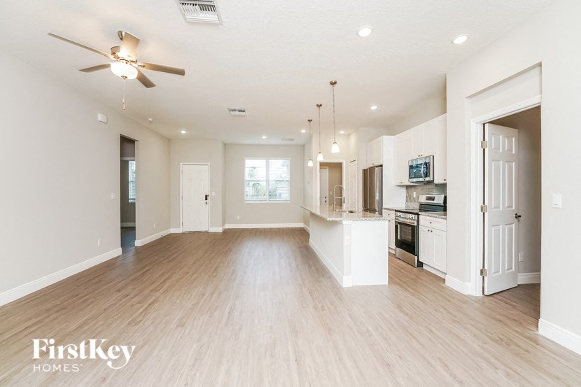 an empty living room and kitchen with a ceiling fan