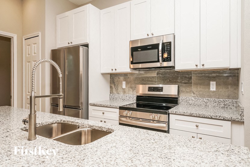 a white kitchen with granite counter tops and stainless steel appliances