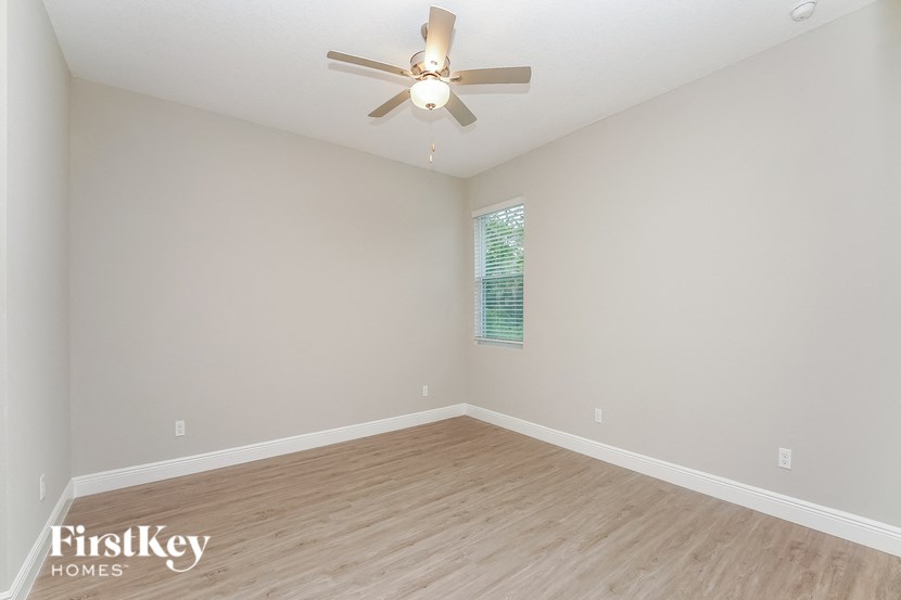 the spacious living room with hardwood flooring and a ceiling fan