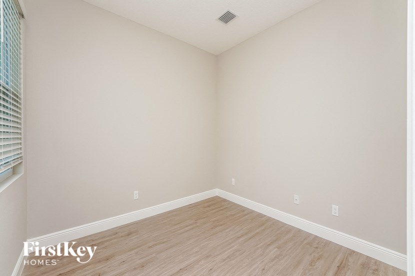 the second bedroom with wood floors and white walls and a window