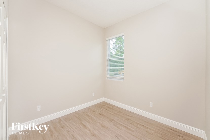 a bedroom with wood floors and white walls and a window