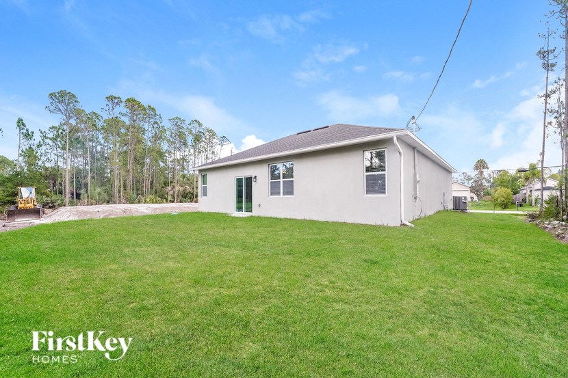 a white house with a grassy yard and trees in the background