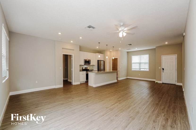 an open living room and kitchen with wood flooring and a ceiling fan