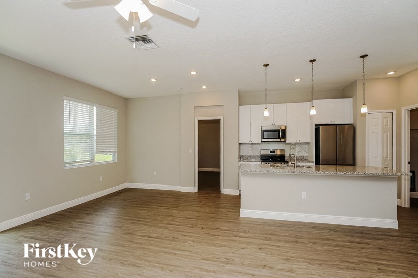 an empty living room with a kitchen with a counter top