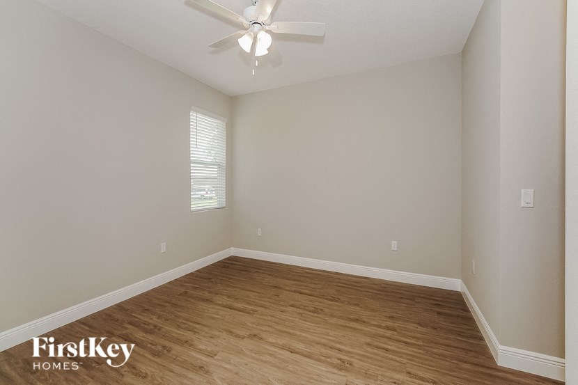 the spacious living room with hardwood flooring and a ceiling fan