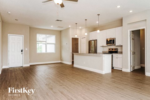 an open kitchen and living room with a kitchen island and white cabinets