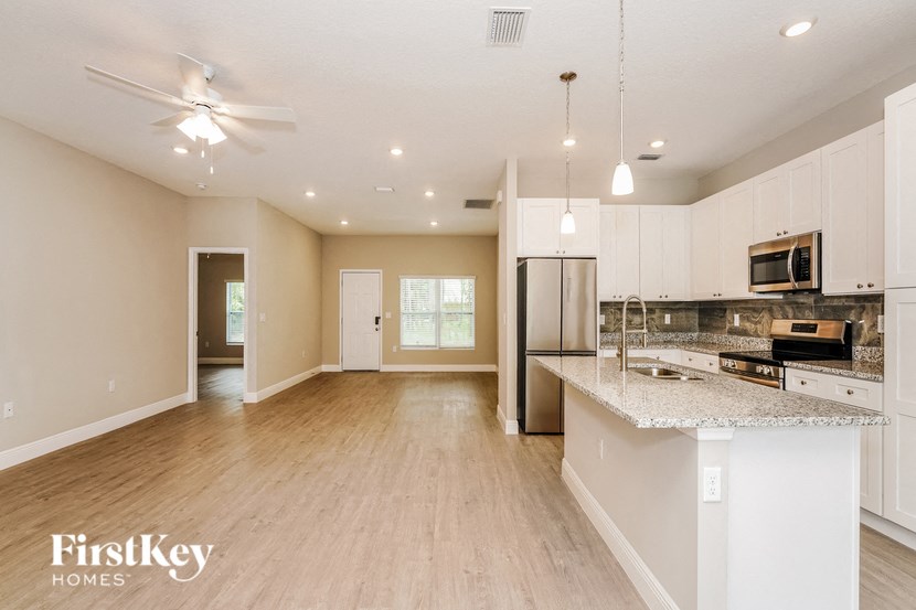 an empty kitchen with white cabinets and a granite counter top