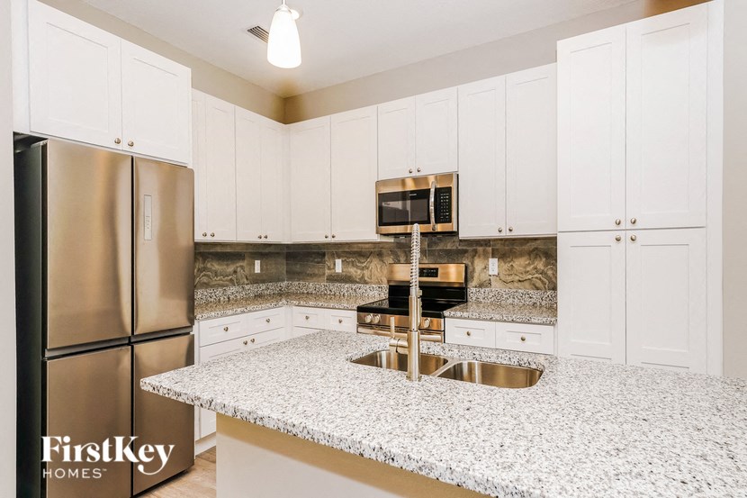 a kitchen with white cabinets and granite counter tops