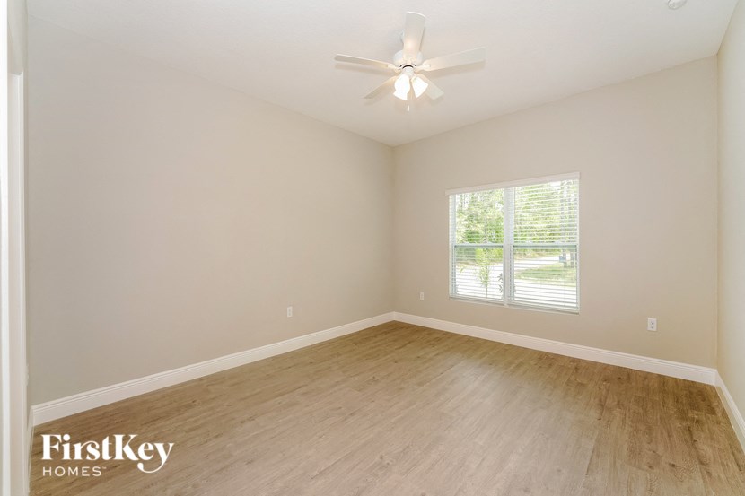 the spacious living room with wood flooring and a ceiling fan