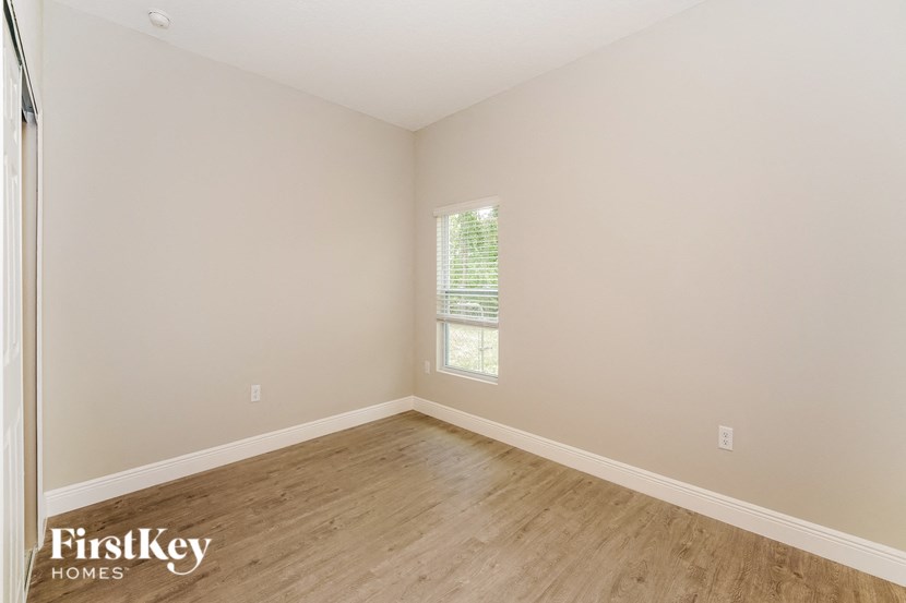 a bedroom with wood floors and white walls and a window