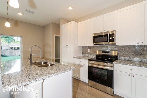A kitchen with white cabinets and a granite countertop.