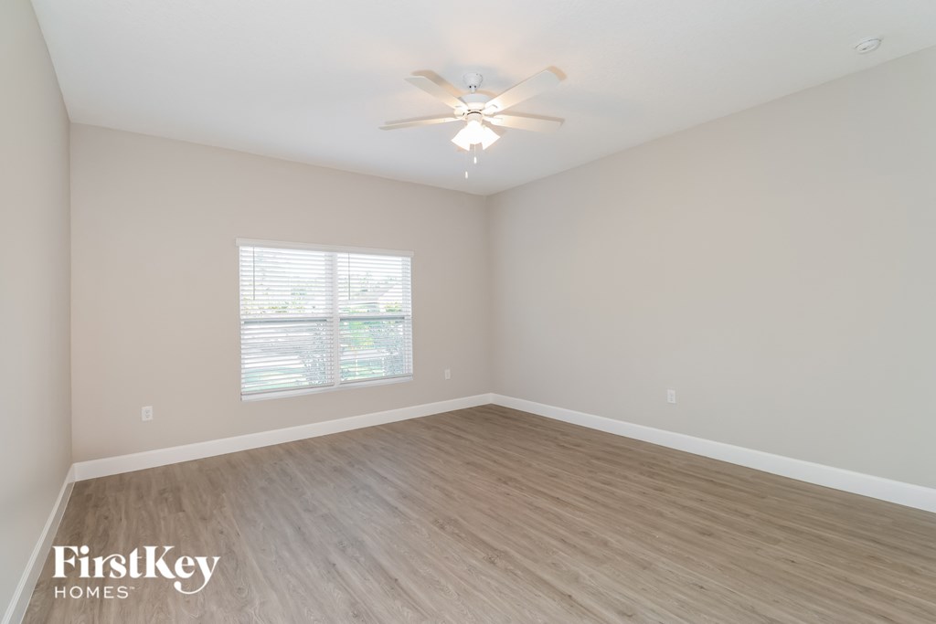A room with a ceiling fan and a window with blinds.