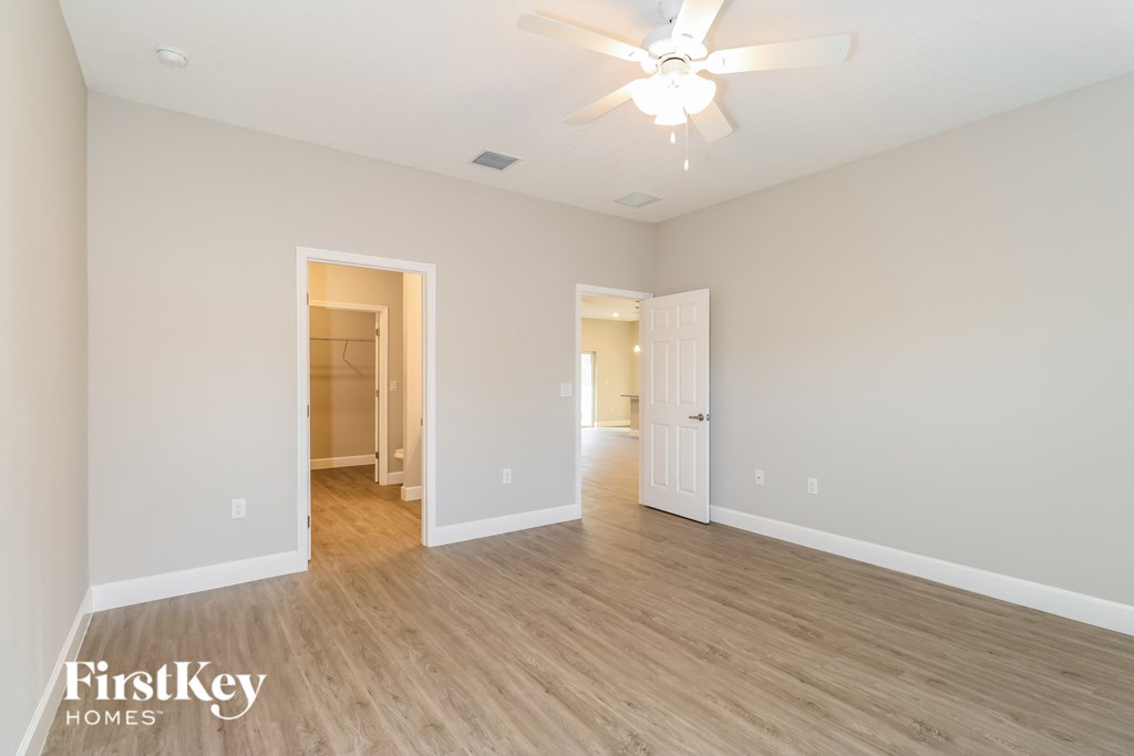 A spacious room with wooden floors and a ceiling fan.