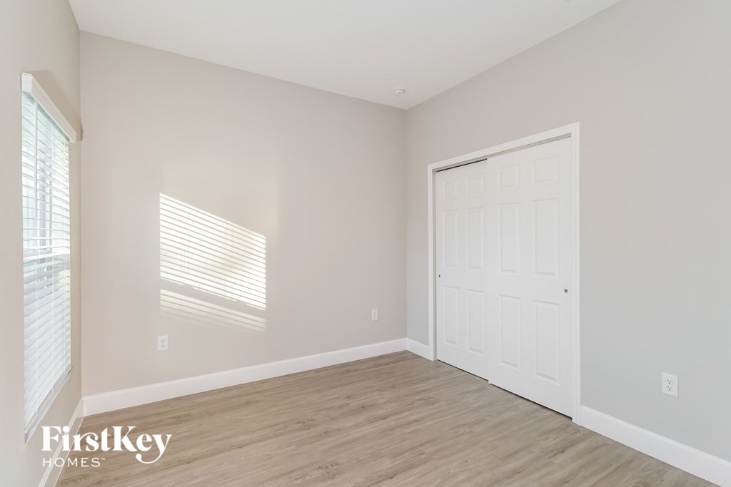 A room with a white door and wooden flooring.