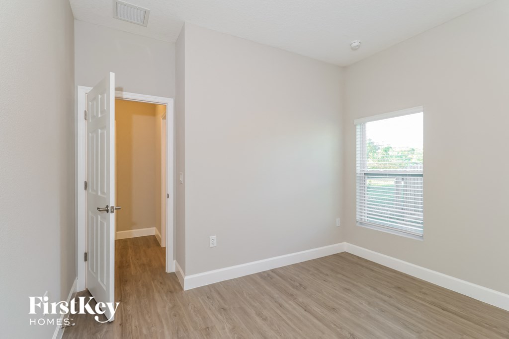 A room with a wooden floor and a window with blinds.