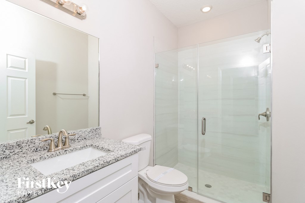 A bathroom with a marble countertop and a walk-in shower.