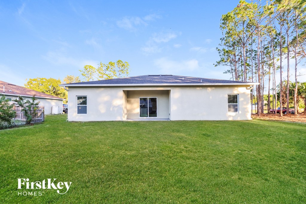 A white house with a black roof is surrounded by a grassy lawn.