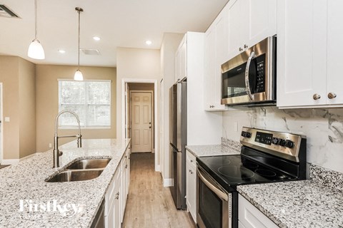 a kitchen with granite counter tops and white cabinets and a sink