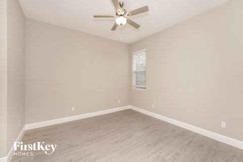 the spacious living room with a ceiling fan and wood flooring