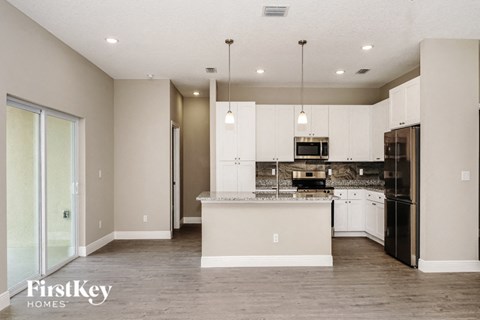 a kitchen with white cabinets and black appliances and a large island