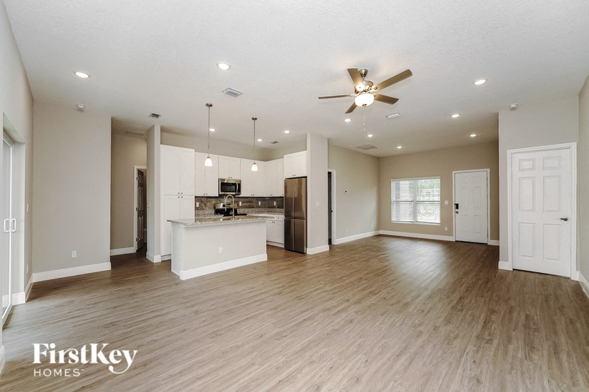 an open kitchen and living room with wood flooring and a ceiling fan