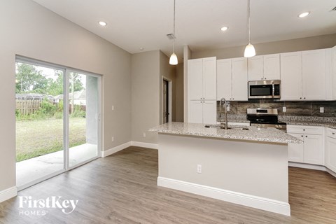 a kitchen with white cabinets and a marble counter top